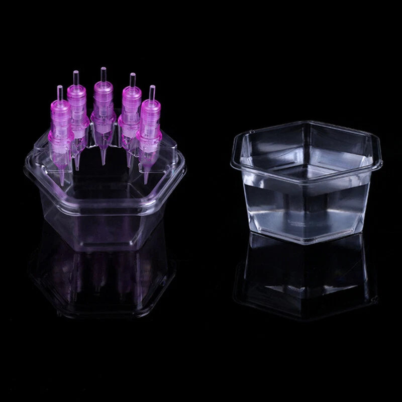 Clear plastic tattoo cartridge holder with pink needles on a black background